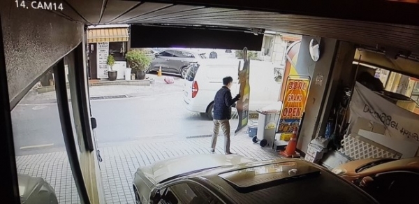 정체 불상의 사람이 식당 앞에 승합차를 세운 뒤 오비맥주 '한맥' 입간판을 무단으로 수거해 트렁크에로 실고 있다. (오비맥주가 입수해 경찰에 증거로 제출한 CCTV 영상 일부.